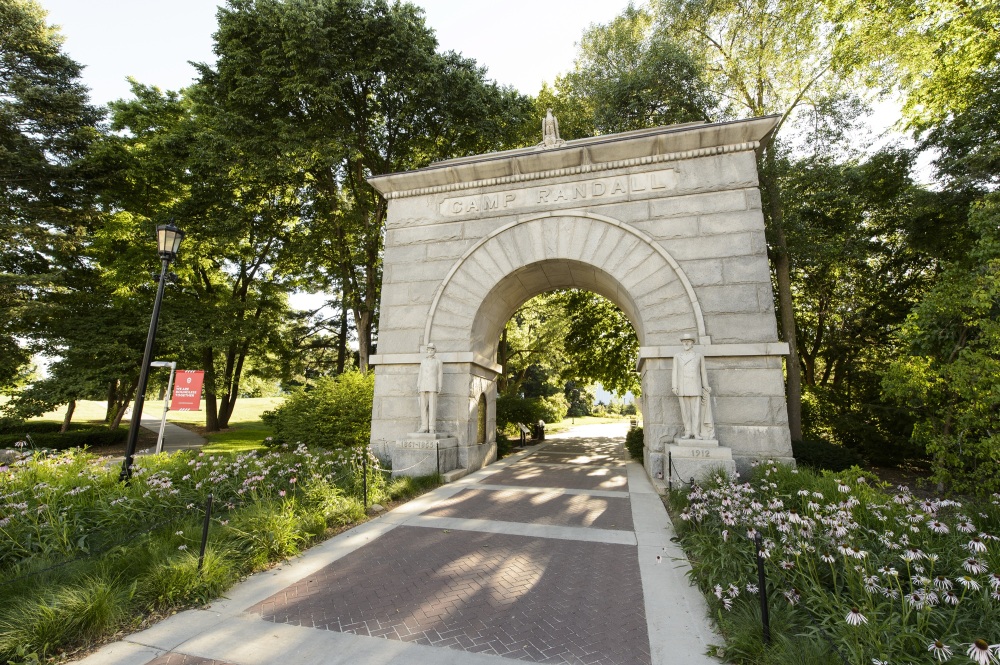 A photo of the stone Memorial Arch with bright green foliage and trees around.